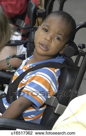 Stock Image - Little boy with multiple disabilities positioned in his wheelchair, and ready for an outing with friends.. Fotosearch