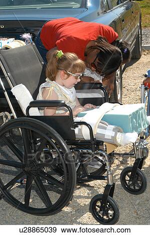 Stock Photo - Little girl with multiple disabilities preparing to attend an event with her friends and family.. Fotosearch
