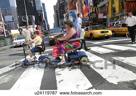 Stock Photo - Mother and son crossing a street in New York City, using scooters/carts, while vacationing there.. Fotosearch