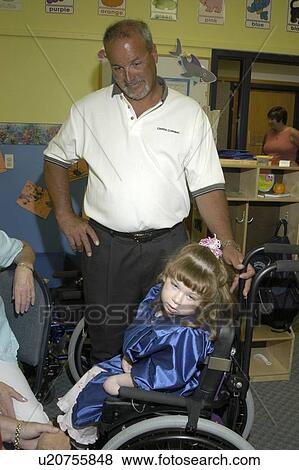 Stock Photo - Proud father with his daughter on the day of her pre-school graduation. His daughter has multiple disabilities and utilizes a wheelchair for mobility.. Fotosearch