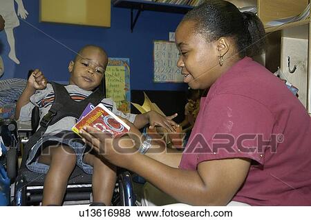 Student with a disability receiving assistance from his teacher to read a book. View Large Photo Image Stock Photo - Student with a disability receiving assistance from his teacher to read a book.. Fotosearch