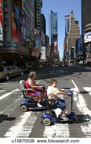 Woman and child crossing a street in New York City, using scooters/carts, while vacationing there. View Large Photo Image Stock Photo - Woman and child crossing a street in New York City, using scooters/carts, while vacationing there.. Fotosearch