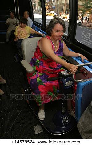 Picture - Woman utilizing a scooter/cart riding a city bus.. Fotosearch