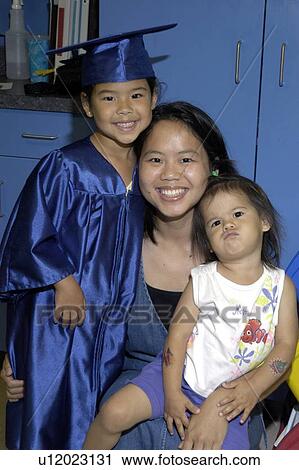 Stock Image - A mother and her two daughters on graduation day. The youngest child has a disability.. Fotosearch