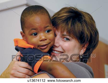 Stock Image - Absolutely adorable image of a toddler with a disability getting a hug from his teacher.. Fotosearch