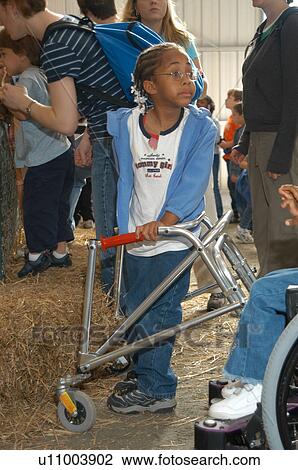 Little girl with a disability, utilizing a walker to assist mobility, looking back for her grandmother. View Large Photo Image Stock Image - Little girl with a disability, utilizing a walker to assist mobility, looking back for her grandmother.. Fotosearch