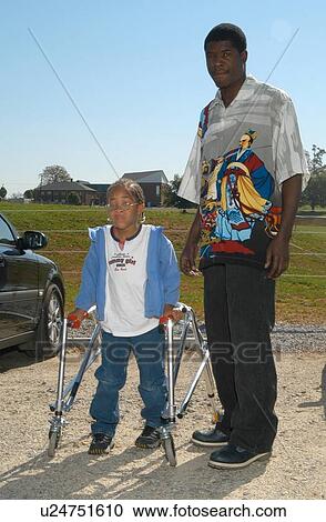Stock Image - Little girl with a disability, utilizing a walker to assist mobility, spending time with her Dad.. Fotosearch