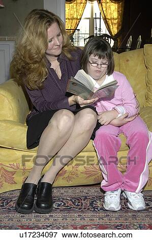 Little girl with Down Syndrome reading a book to her mother. View Large Photo Image Stock Photo - Little girl with Down Syndrome reading a book to her mother.. Fotosearch