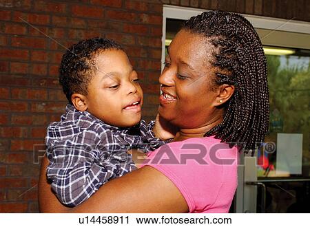 Woman holding a cute little boy who has disabilities. View Large Photo Image Stock Image - Woman holding a cute little boy who has disabilities.. Fotosearch