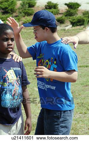 Stock Image - Young man with a disability, DownÆs Syndrome, participating in group activities with his friends.. Fotosearch