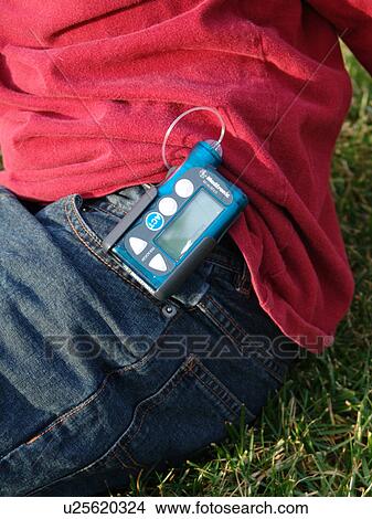 A young boy clips on his insulin pump to his jeans. View Large Photo Image Picture - A young boy clips on his insulin pump to his jeans.. Fotosearch