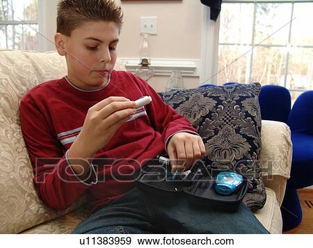 A young boy sits on the couch and gets ready to take an insulin test. View Large Photo Image Stock Photo - A young boy sits on the couch and gets ready to take an insulin test.. Fotosearch