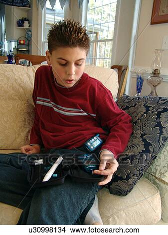 A young boy sits on the couch while taking an insulin test. View Large Photo Image Picture - A young boy sits on the couch while taking an insulin test.. Fotosearch