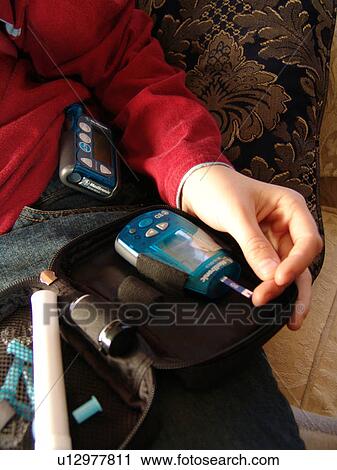 Stock Image - A young person takes an insulin test.. Fotosearch