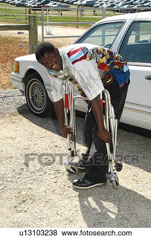 Stock Photo - Man folding a walker to place in a vehicle for use by a person with a disability.. Fotosearch