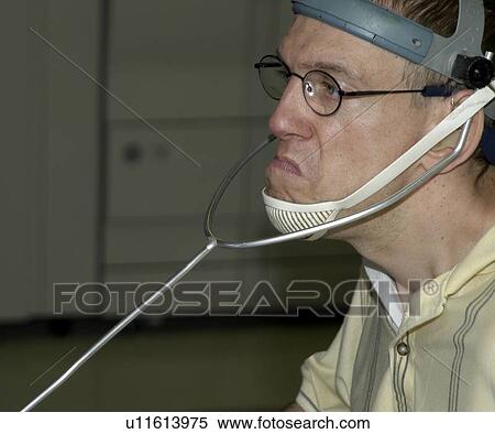 Stock Photography - Man with significant disabilities utilizing headgear to operate communications apparatus.. Fotosearch