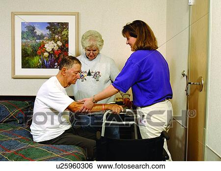 Older man with a disability receiving assistance from his wife and a therapist to transfer from the bed to the use of a walker. View Large Photo Image Stock Photograph - Older man with a disability receiving assistance from his wife and a therapist to transfer from the bed to the use of a walker.. Fotosearch