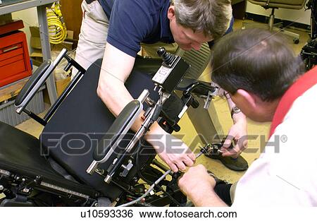 Two men repairing a wheelchair. View Large Photo Image Stock Photograph - Two men repairing a wheelchair.. Fotosearch