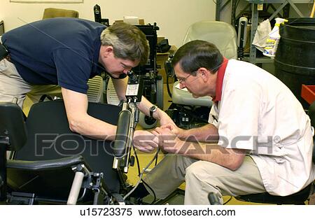 Two men repairing a wheelchair. View Large Photo Image Stock Photography - Two men repairing a wheelchair.. Fotosearch