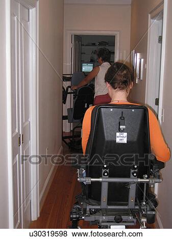 Young woman using an electric wheelchair follows her Mother down a hallway. View Large Photo Image Stock Photo - Young woman using an electric wheelchair follows her Mother down a hallway.. Fotosearch