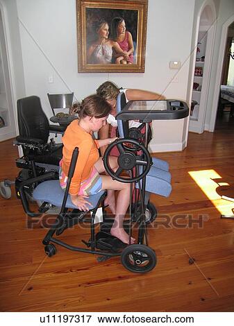 Stock Photo - Young woman (wheelchair user) uses a ôstanderö (assistive device) to lengthen her tendons.. Fotosearch