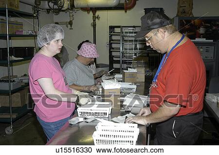 Stock Image - A group of people with disabilities working together in a commercial kitchen.. Fotosearch