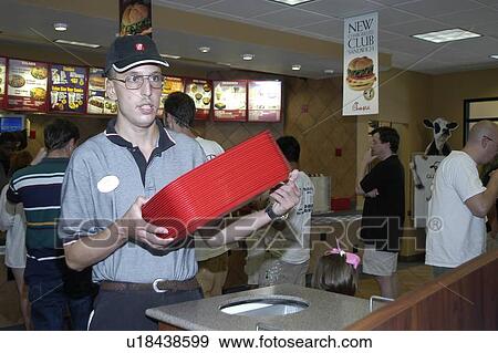 Stock Photo - A man with a disability emptying the trash at a fast food restaurant.. Fotosearch