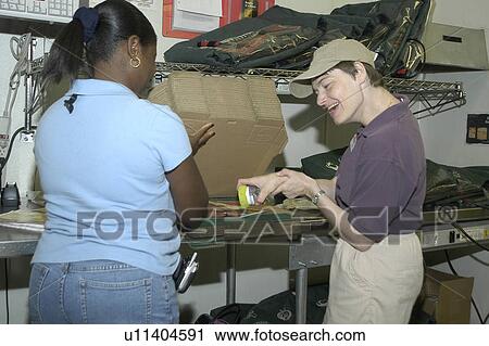 Stock Image - A person with disabilities getting help slicing a pizza.. Fotosearch