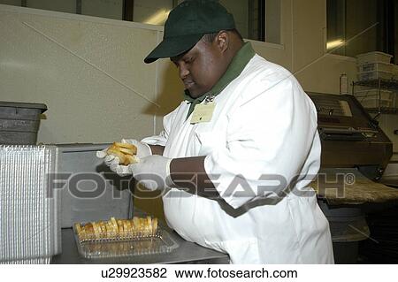 Stock Image - Man with disabilities packaging bread in a food store.. Fotosearch