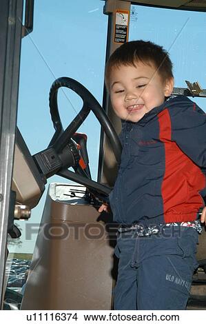 Picture - Cute little boy with disabilities in the cab of a tractor.. Fotosearch