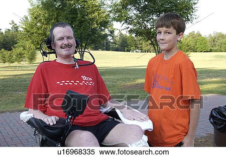 Stock Photography - Man with a disability and his son spending time together in the park.. Fotosearch