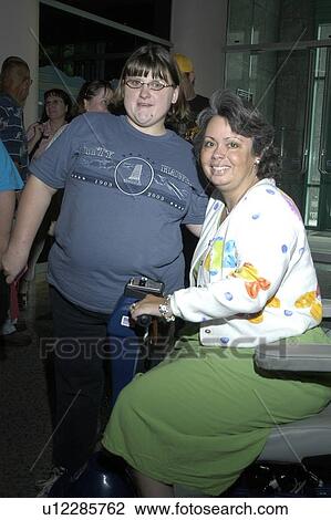 Stock Image - Two women with disabilities (one with physical disabilities, one with cognitive disabilities) smiling for the camera.. Fotosearch