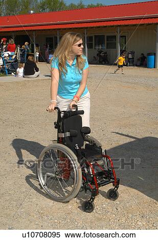 Stock Photography - Woman pushing wheelchair for a child.. Fotosearch