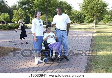 Stock Image - Young woman with a disability spending time with a couple of friends in the park.. Fotosearch