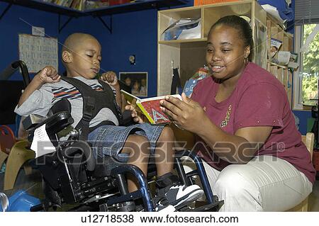 Boy with significant disabilities listening to a story read by his caregiver. View Large Photo Image Stock Photo - Boy with significant disabilities listening to a story read by his caregiver.. Fotosearch