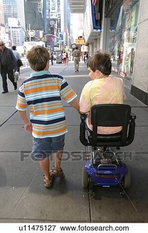 Brothers, one using a scooter, going down a city sidewalk. View Large Photo Image Stock Photo - Brothers, one using a scooter, going down a city sidewalk.. Fotosearch