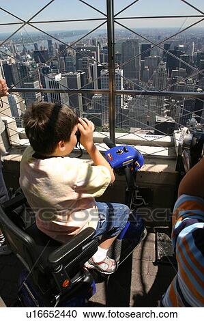 Stock Image - Child using a scooter looking over the city.. Fotosearch