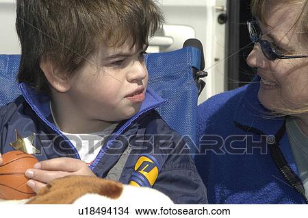 Close shot of boy (autistic) in a wheelchair next to his Mom View Large Photo Image Picture - Close shot of boy (autistic) in a wheelchair next to his Mom. Fotosearch
