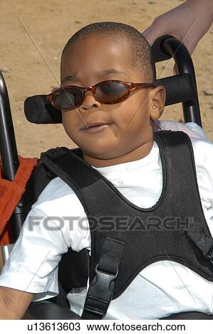 Stock Image - Really cool little guy with multiple disabilities on an outing with family and friends.. Fotosearch