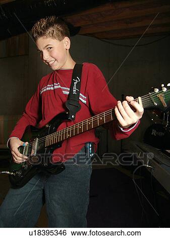 A young boy enjoys playing with his guitar. View Large Photo Image Stock Photograph - A young boy enjoys playing with his guitar.. Fotosearch