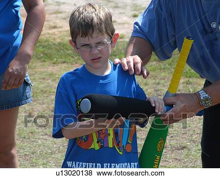 Stock Photo - Boy with disabilities getting some assistance to play baseball with friends.. Fotosearch