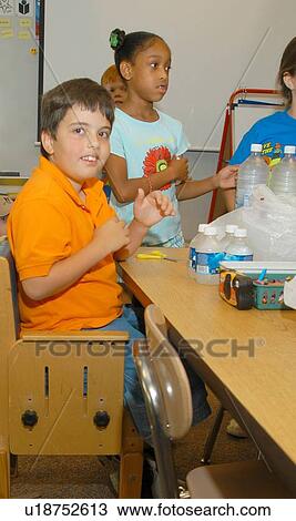 Stock Image - Boy with Muscular Dystrophy working with classmates on a school project. He is utilizing a positioning chair to provide proper support for his body.. Fotosearch