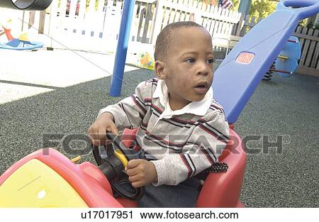 Cute little boy with a disability playing in a paddle car on the playground at school. View Large Photo Image Stock Image - Cute little boy with a disability playing in a paddle car on the playground at school.. Fotosearch