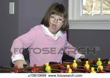 Girl with Down Syndrome playing a game of ôfoozballö. View Large Photo Image Stock Photo - Girl with Down Syndrome playing a game of ôfoozballö.. Fotosearch