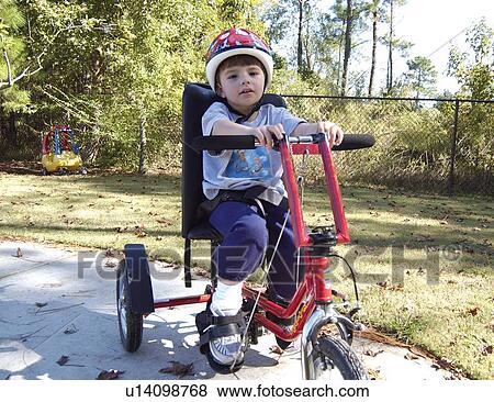 Great image of a little boy with multiple disabilities independently riding his adapted bicycle/tricycle. View Large Photo Image Stock Photo - Great image of a little boy with multiple disabilities independently riding his adapted bicycle/tricycle.. Fotosearch