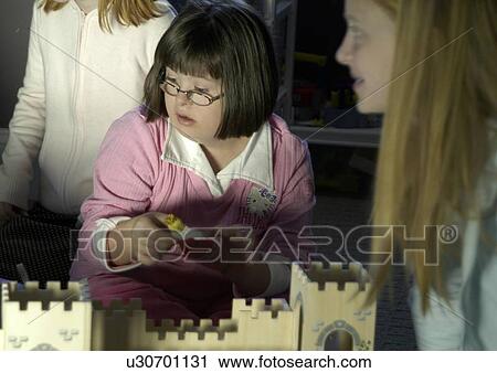 Stock Image - Little girl with Down Syndrome playing with a castle.. Fotosearch
