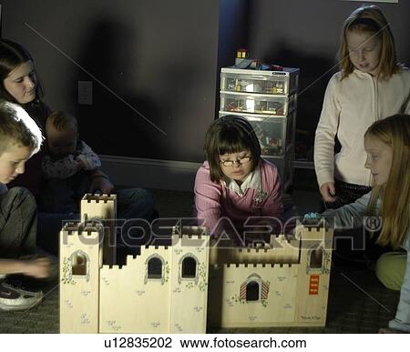 Stock Image - Several children, one with Down Syndrome, playing together with various toys and games.. Fotosearch
