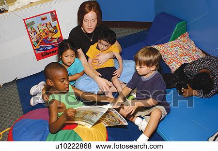Stock Photo - Teacher and children with and without disabilities at story time, reading and discussing books they are reading.. Fotosearch