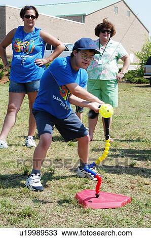 Stock Image - Teenage boy with DownÆs Syndrome participating in a game of t-ball with friends.. Fotosearch