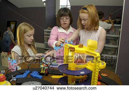 Picture - Three children, one with Down Syndrome, playing with toys.. Fotosearch